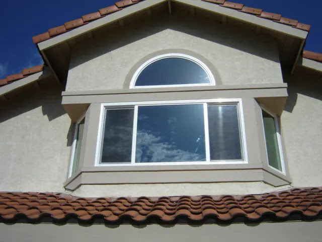 Stucco home exterior with bay and arched windows for window replacement Temecula, CA homeowners