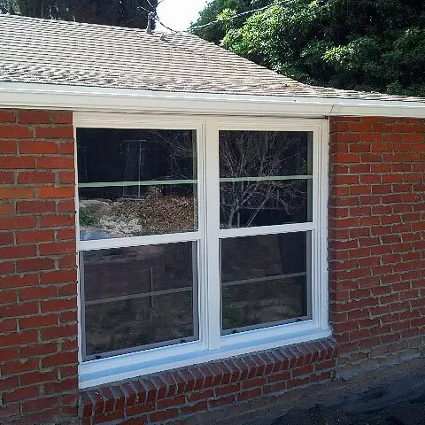 Modern white replacement windows installed on a brick home exterior in Corona, CA.
